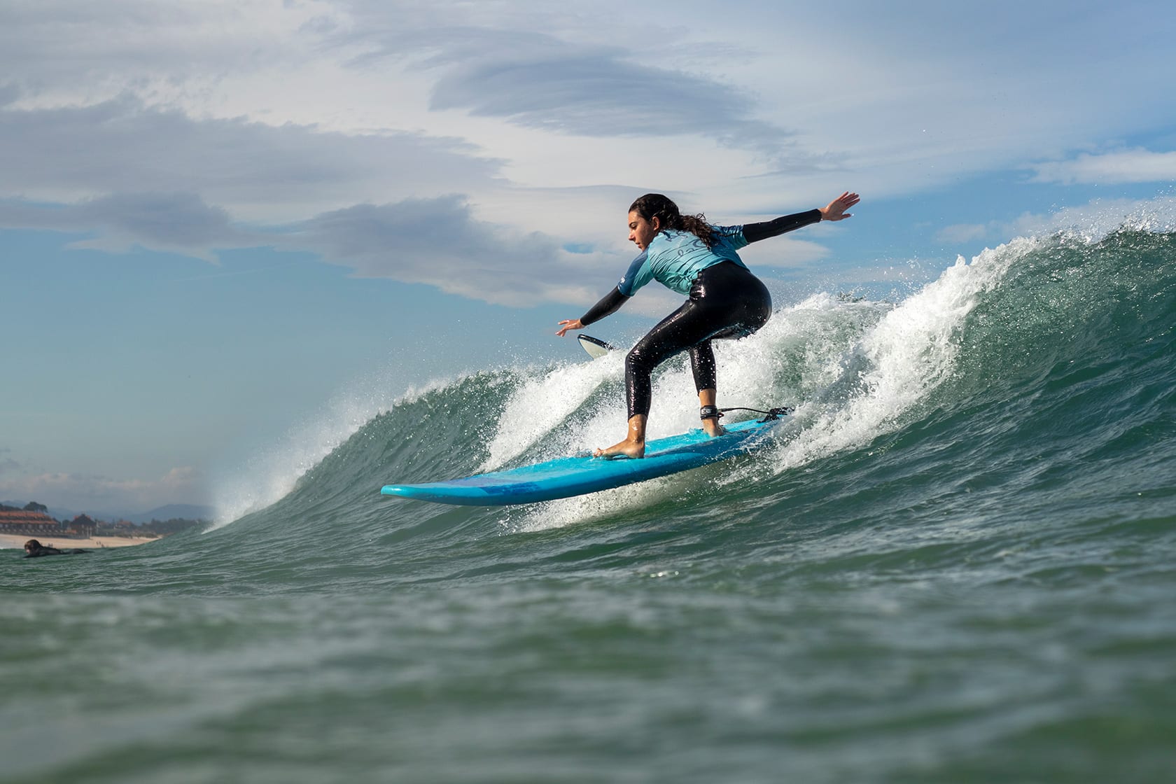 Grupo de alumnos de la escuela en el agua encima de sus tablas durante la clase de surf esperando a la ola y riendo