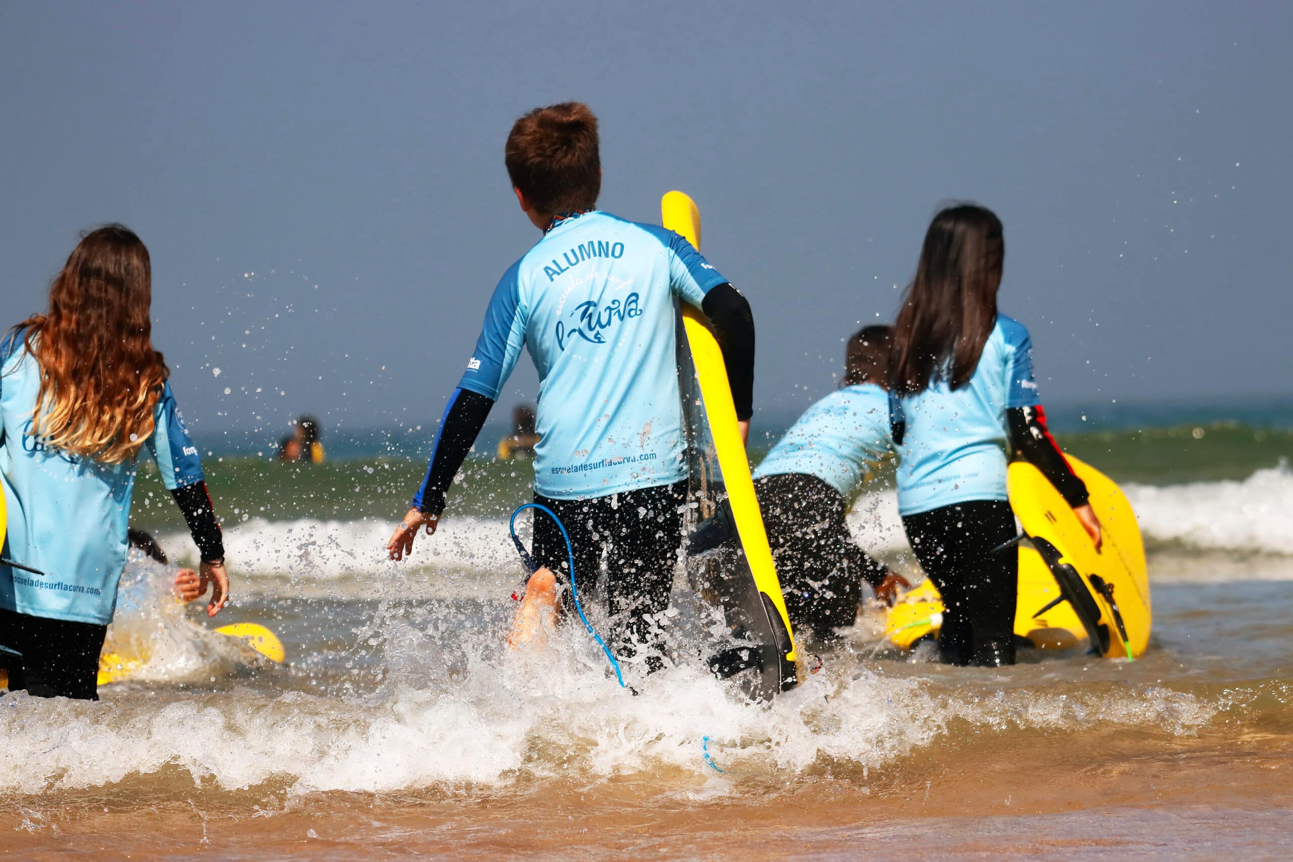 menores entrando al agua para surfear