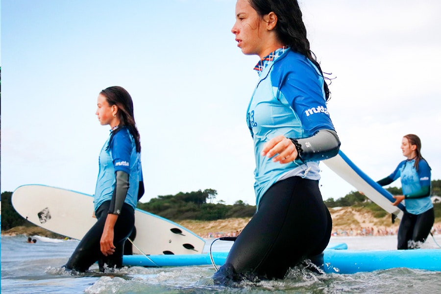 alumnas entrando al agua con tablas