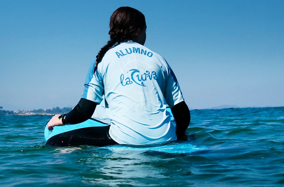 Alumna en clse de surf esperando una ola