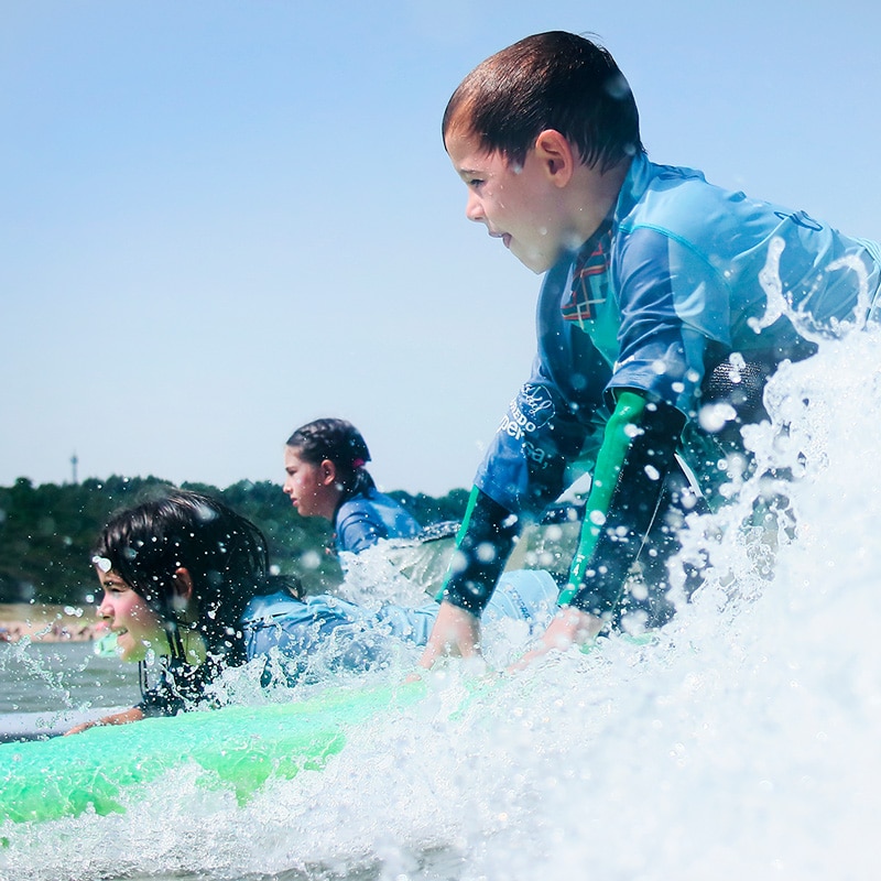 surf camp menores en el agua surfeando espumas