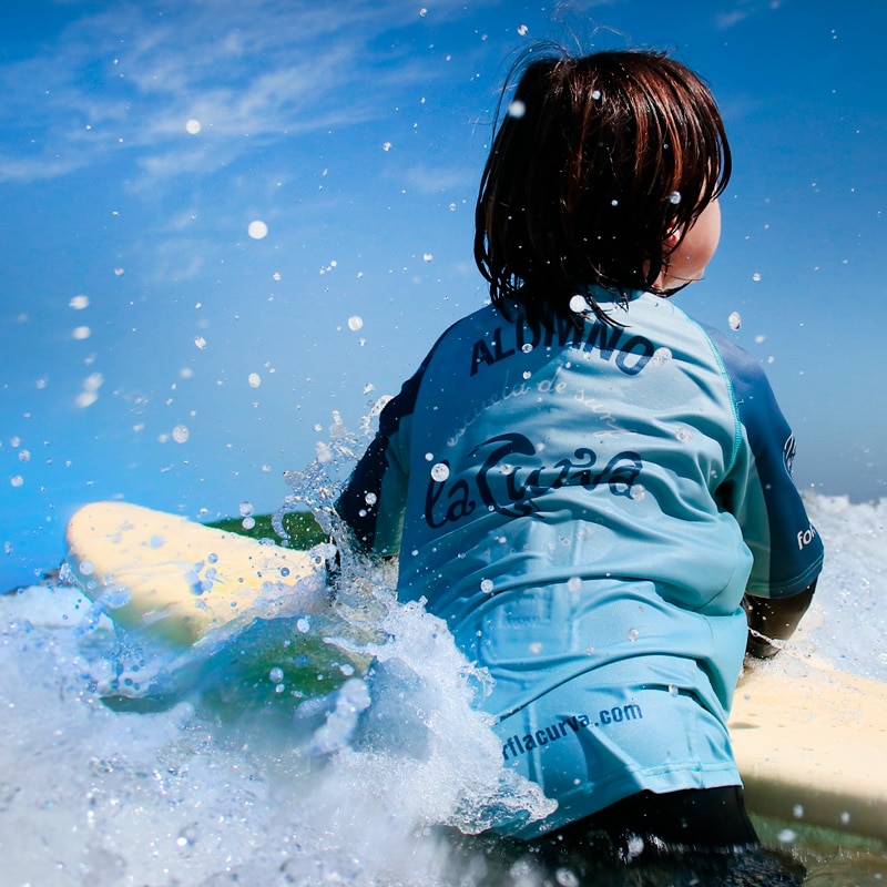 nino en el agua disfrutando de la clase de surf en el surf camp diurno